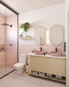 a bathroom with pink tiles and two round mirrors