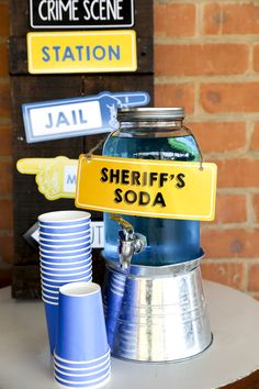 there is a sign that says sheriff's soda next to cups on a table