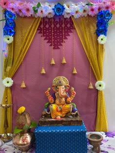 an idol sitting on top of a blue box in front of a purple wall with flowers