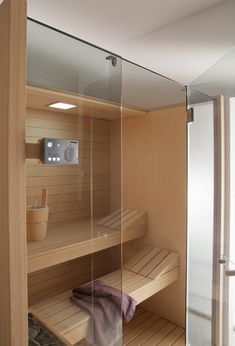 the inside of a wooden sauna with glass walls and shelves on each side,