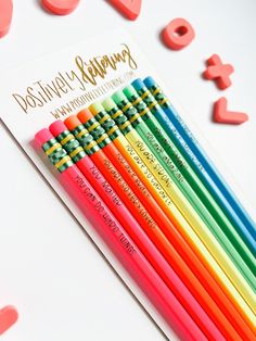 six colored pencils sitting next to each other on a white surface with letters and numbers around them