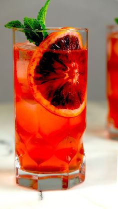 a close up of a drink in a glass filled with ice and garnish