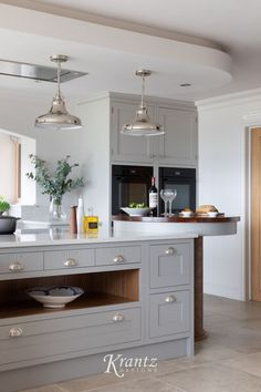 a kitchen with two pendant lights hanging from the ceiling and an island in front of it