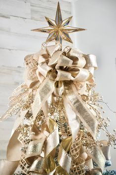 a christmas tree decorated with gold and silver ribbon, stars and ribbons on it's top