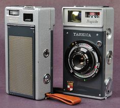 an old fashioned camera sitting on top of a table next to a brown leather case