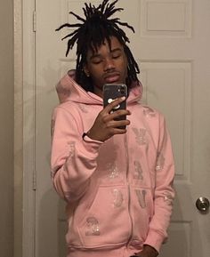 a young man with dreadlocks looking at his cell phone while standing in front of a door