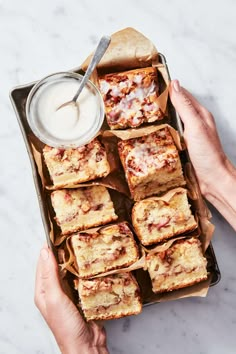 someone is holding a tray full of food and dipping sauce on top of the bread