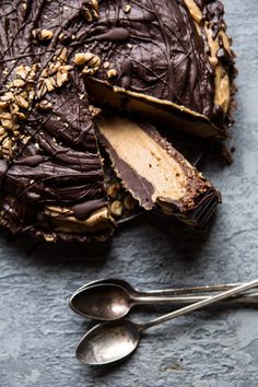 a piece of chocolate cake sitting on top of a table next to two spoons