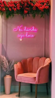 a pink chair sitting in front of a neon sign