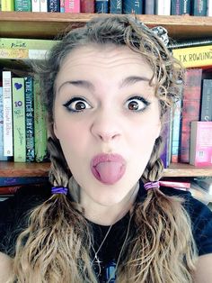 a woman sticking her tongue out in front of bookshelves