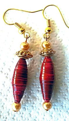 two red glass beads are hanging from gold plated earwires on a white cloth