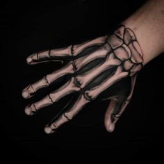 a hand with black and white tattoos on it, showing the skeleton's hands