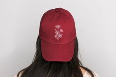 Spruce up your go-to baseball cap or dad hat with sweet hand-embroidered flowers! The perfect way to hide your bed head or make an (understated) statement. This design is stitched in a creamy white color on a burgundy cap. These hats are adjustable with a brass buckle in the back and fit most head shapes/sizes. *DETAILS* -100% cotton  -Low profile -Adjustable with small metal buckle -6 panels -One size fits most Embroidered design is approximately 1.75" x 3" *CARE INSTRUCTIONS* -Washing: Your hand-embroidered hat can be washed in your washing machine on a delicate setting, but for best results and to preserve the embroidered design, I recommend washing by hand. -Drying: For best results, I recommend hanging or laying out to dry. However, you can also tumble dry on a low heat setting.  Have Embroider Hat, Funny Bucket Hats, Poppy Hat, Daisy Hat, Burgundy Hat, Stitch Tshirt, Embroidered Bucket Hat, Hat Flower, Embroidery Leaf