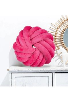 a large pink ball sitting on top of a white dresser next to a round mirror