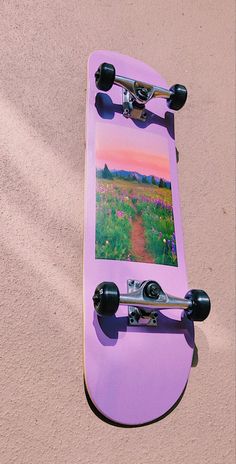 a purple skateboard laying on top of a sand covered ground next to a tree