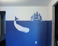 a room painted with a whale and boat on the wall