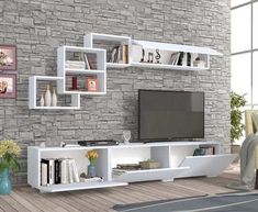 a white entertainment center with bookshelves and pictures on the brick wall behind it