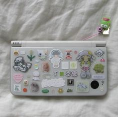 a laptop with many stickers on it sitting on a white sheet next to a stuffed animal