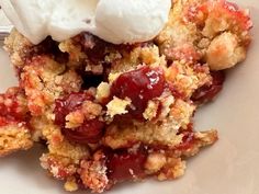 a white plate topped with fruit cobbler and ice cream on top of it's crumbs