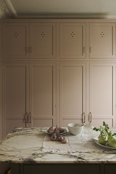 a kitchen counter topped with lots of cupboards next to a bowl of fruit and vegetables