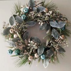 a christmas wreath hanging on the wall with ornaments and greenery in front of it