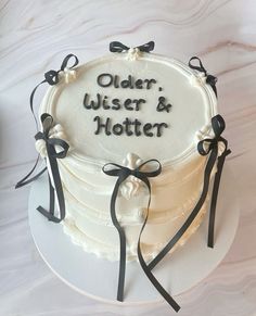 a white cake with black ribbons and the words older, wiser & holter on it