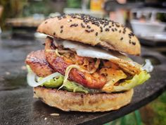 a bacon, egg and lettuce sandwich on a bun with sesame seeds is sitting on a table