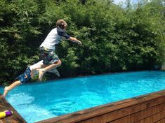 a man jumping into a swimming pool in his backyard