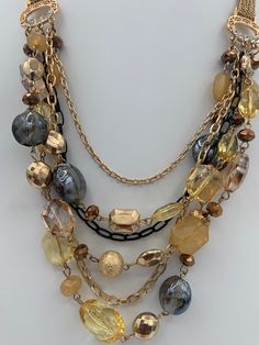 "Beautiful elegant multilayered necklace.  Lobster claw closure. Shortest layer is 23 \", longest 28\", extension 3\".  Six layers , 3 with beads and three without, only chains.  Beads include crystals, glass beads, foiled beads, acrylic beads.  Chains are one black and two gold tone. Connectors have clear rhinestones.  Weight 3.5 oz." Multi-strand Gold Beads Costume Jewelry, Costume Jewelry Beaded Double Strand Necklace, Gold-tone Multi-strand Layered Jewelry, Costume Jewelry Double Strand Beaded Necklace, Double Strand Beaded Chain Costume Necklace, Beaded Double Strand Costume Necklace, Multi-strand Gold Beaded Necklaces For Jewelry Making, Gold Double Strand Costume Jewelry, Multi-strand Gold Beaded Necklace For Jewelry Making