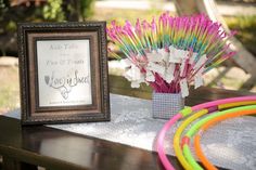 there is a picture frame on the table next to some colorful bracelets and flowers