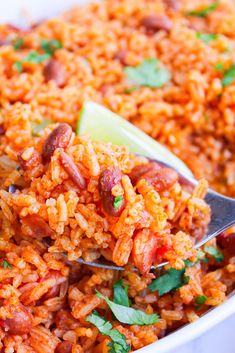 a spoon full of mexican rice with beans and cilantro on top, in a white bowl