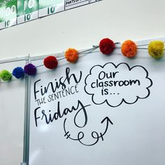 a white board with writing on it and pom - poms around the edges