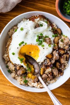 a bowl filled with rice, meat and an egg on top next to a spoon