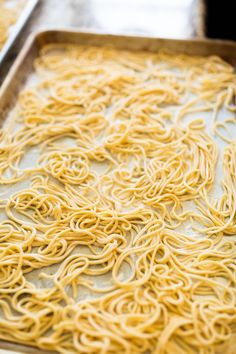 a pan filled with noodles on top of a metal tray next to other food items