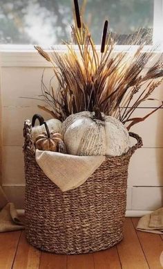 a basket filled with lots of different types of fall decorations on top of a wooden floor