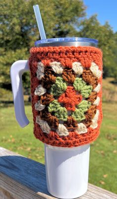 a crocheted coffee cup cozys up with a straw in it's holder