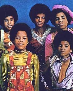 the jacksons pose for a portrait in front of a blue background wearing colorful outfits