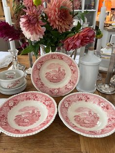 three pink and white plates sitting on top of a table next to a vase filled with flowers