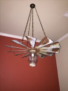 an old fan hanging from the ceiling in a room with red walls and a light fixture