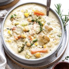 a white bowl filled with chicken and vegetable chowder next to two bowls of soup