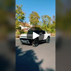 a white truck driving down a street next to trees