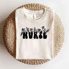 a white t - shirt with the word nurse printed on it next to a wicker basket