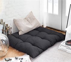 a black futon bed sitting on top of a wooden floor next to a window