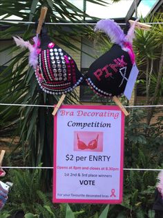 bra decorating competition sign hanging from clothes line in front of palm trees and plants