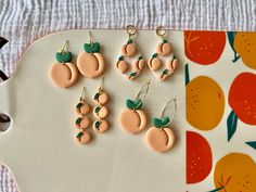 nine peaches and green leaves are hanging from gold earwires on a platter