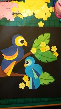 paper cut out of birds sitting on a tree branch with flowers and leaves around them