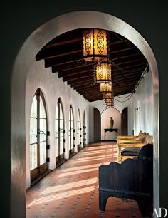 an archway leading into a room with arched windows and wooden benches on the floor in front of them