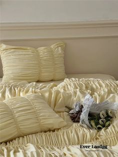 a bouquet of flowers sitting on top of a bed with ruffled sheets and pillows