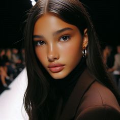 a woman with long dark hair and large hoop earrings on her head at a fashion show