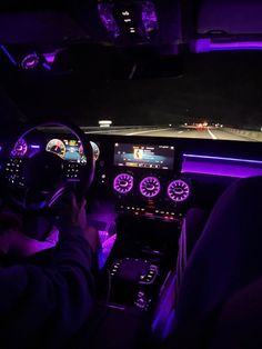 the interior of a car is lit up with purple lights and features electronic dashboard controls